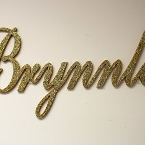 May include: Gold glitter letters spelling out the name "Brynnley".