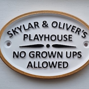 May include: White oval sign with a gold border. The sign reads "Skylar & Oliver's Playhouse No Grown Ups Allowed".