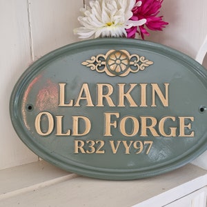 Könnte beinhalten: Ein grünes ovales Schild mit goldener Beschriftung, auf dem "Larkin Old Forge R32 VY97" steht.