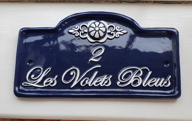 Puede incluir: Un letrero de n&uacute;mero de casa azul y blanco con el n&uacute;mero 2 y el texto "Les Volets Bleus".