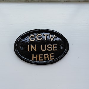 CCTV in use here,house sign , pub sign,security camera.