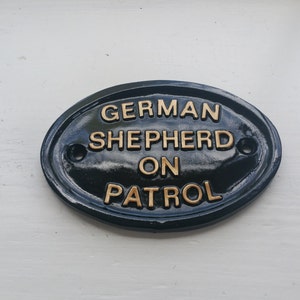 Schild ""Schäferhund auf Streife"" aus schwarzem & goldenem Kunstharz."
