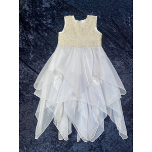 May include: White sleeveless dress with a layered tulle skirt and a beaded bodice.