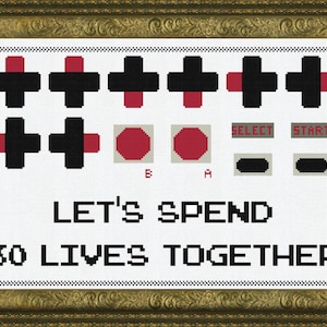 May include: A white cross-stitch pattern with a pixelated design of a video game controller, buttons, and the text "Let's Spend 30 Lives Together".