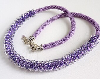 May include: A purple beaded necklace with a gradient of color from light to dark. The necklace is made with small, round beads and has a silver clasp.