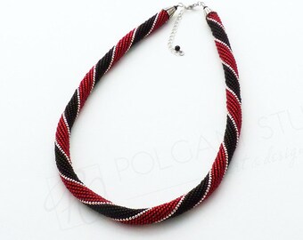 May include: A red and black beaded necklace with a silver chain and clasp. The necklace is twisted into a spiral shape.