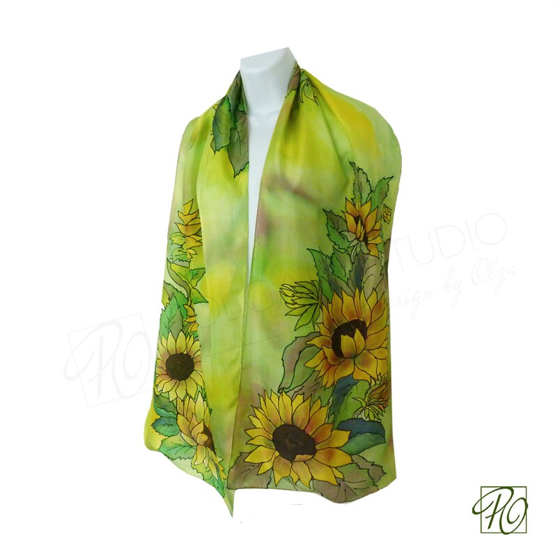 May include: A green silk scarf with a hand-painted design of sunflowers. The scarf is on a white background.