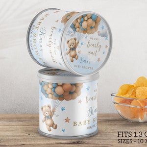 May include: Blue and brown chip can label with a teddy bear holding balloons. The label says "We can bearly wait" and "Karas Baby Shower". The label fits 1.3 oz chip cans and is editable with Canva.