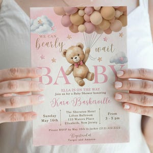 May include: Pink and white baby shower invitation with a teddy bear holding balloons. The invitation reads "We can barely wait Baby Ella is on the way. Join us for a Baby Shower honoring Kara Baskerville. The Sheraton Hotel Lifton Ballroom 133 Waters Place Elizabeth, New Jersey. Sunday May 16th From 3-5 pm. Please RSVP by May 10th to Jackie (212) 222-2222. Registered at Target and Amazon."