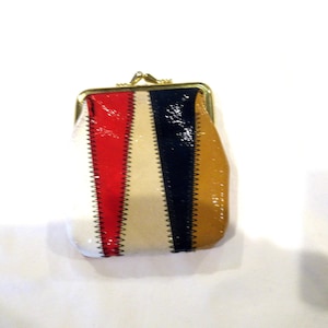 May include: A small, vintage coin purse with a gold clasp. The purse is made of a striped fabric with red, white, blue, and yellow stripes.