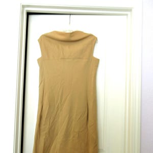 May include: A sleeveless, tan dress with a scoop neck and a straight, A-line silhouette.