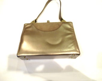 May include: A gold-colored leather handbag with a top flap closure and a single handle.