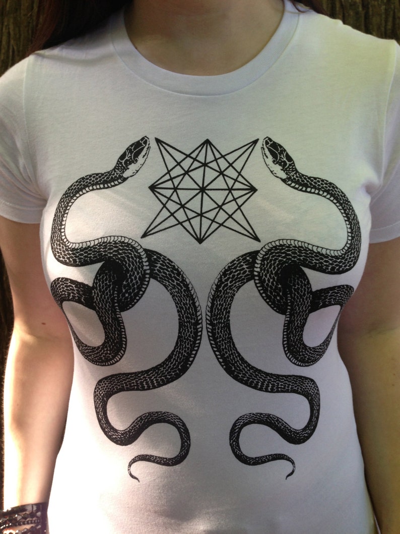 K&ouml;nnte beinhalten: Wei&szlig;es T-Shirt mit einem schwarz-wei&szlig;en grafischen Design aus zwei Schlangen, die sich um einen geometrischen Stern winden.