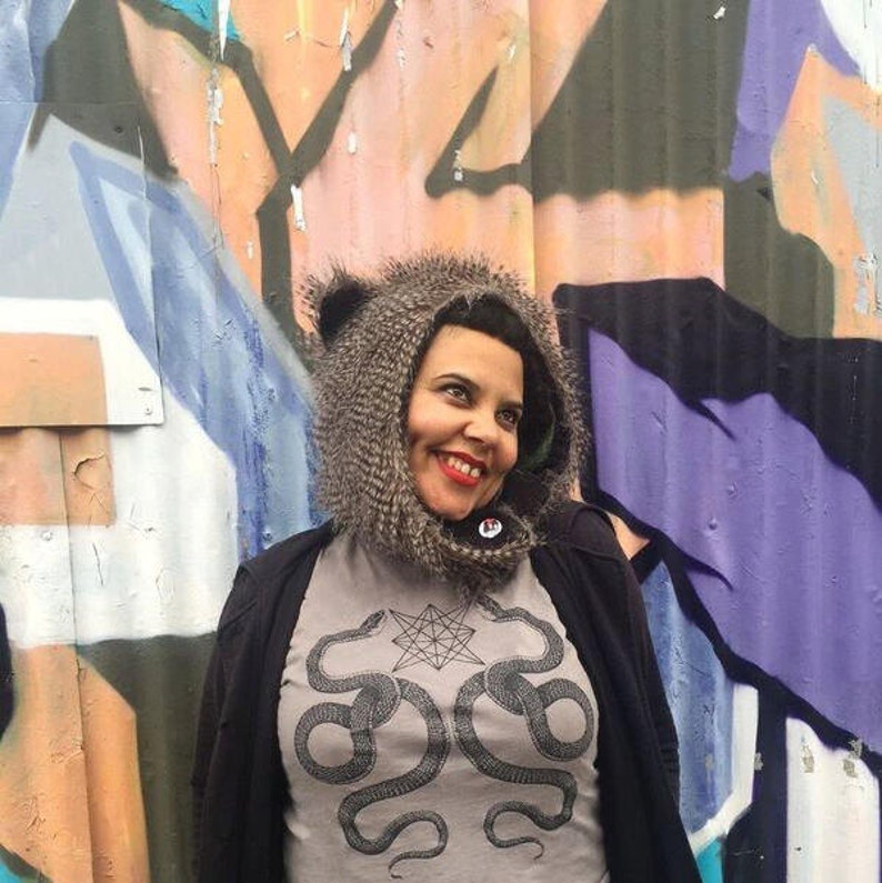 K&ouml;nnte beinhalten: Eine Frau tr&auml;gt einen grauen Kapuzenpullover mit einem schwarzen und wei&szlig;en Schlangenmotiv und dem Text "Shroom Queens".