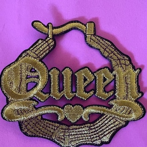 May include: Gold embroidered iron-on patch with the word "Queen" in a stylized font. The patch features a heart and a crown design.