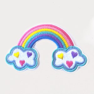 May include: A rainbow-colored embroidered patch with clouds and hearts. The rainbow has pink, yellow, green, blue, and purple stripes. The clouds are white with blue outlines and have yellow and pink hearts.