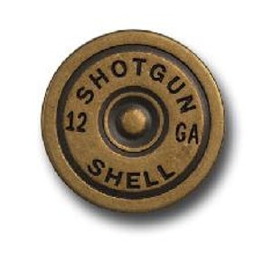 May include: A round, antique brass-colored button with the words "SHOTGUN SHELL" and "12 GA" embossed around the center. The button has a raised, circular design in the center.