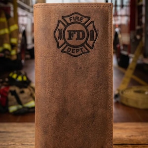 May include: Brown leather wallet with a debossed Fire Department emblem. The wallet features the text "FIRE FD DEPT" within a Maltese cross design. The wallet is rectangular and appears to be closed.