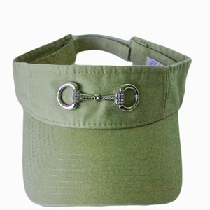 May include: A green visor with a silver and rhinestone horse bit accent.