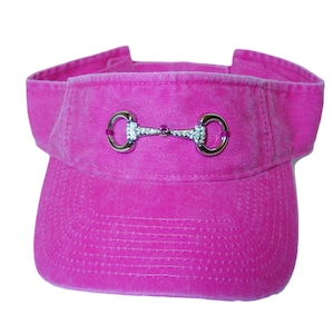 May include: A pink visor with a silver equestrian-style bit with rhinestones.