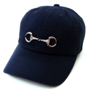 May include: A navy blue baseball cap with a silver equestrian-style bit with rhinestones on the front.