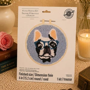 May include: A punch needle kit featuring a French bulldog wearing blue glasses on a light blue background. The packaging displays the text Punch Needle Kit, Loops & Threads, and Finished size 6 in (15.2 cm) round. The kit includes fabric and floss.