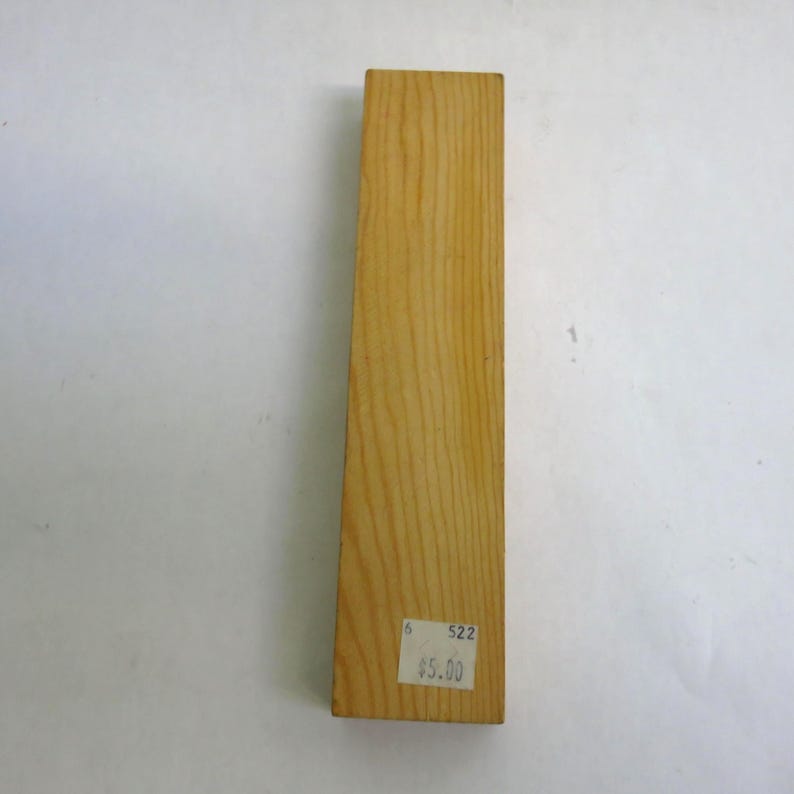 May include: A rectangular piece of light-colored wood with visible grain. A price tag is affixed to the bottom right corner. The tag has the number "6" and "522" printed on it, along with the price.