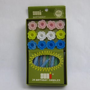 May include: A box of Suni brand birthday candles. The box is green with a yellow sun design. The box contains 24 candles, each 2.5 in. x 3/8 in., and flower-shaped candle holders in pink, white, yellow, and blue.