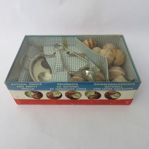 May include: Vintage escargot set in a box with a blue and white checkered pattern. The set includes a small metal pot, tongs, and a spoon. The box is labeled "Natural Snails and Empty Shells."