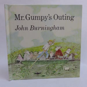 May include: A hardcover children's book titled Mr. Gumpy's Outing by John Burningham. The cover features a color illustration of a man in a yellow hat poling a boat filled with various animals and children across a green river landscape.