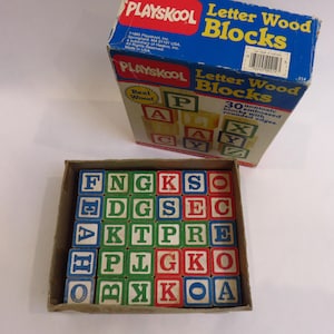 May include: A vintage Playskool Letter Wood Blocks set. The blue box displays the brand name and product details. Inside, a tray holds 30 embossed, non-toxic wooden blocks with rounded edges, each featuring a letter in red, green, blue, or yellow.