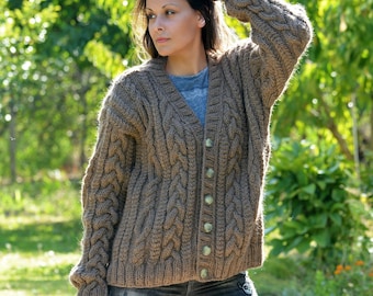 May include: A brown cable knit cardigan with a button closure. The cardigan is made of a soft, chunky yarn and has a relaxed fit.