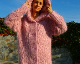 May include: A pink fuzzy hooded cardigan with a cable knit pattern and button closure.