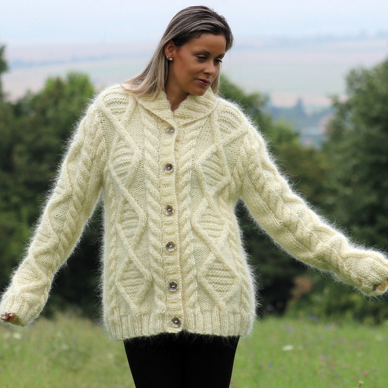May include: A cream-colored fuzzy cardigan with a cable knit pattern and button closure.