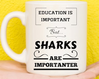 Può includere: Tazza in ceramica bianca con una grafica nera che recita "L'istruzione è importante, ma... Gli squali sono più importanti".