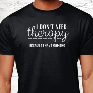 May include: Black t-shirt with white text that reads "I don't need therapy because I have gaming".