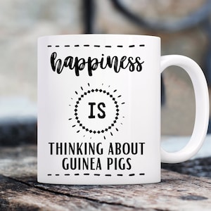 May include: White ceramic mug with black text that reads "happiness is thinking about guinea pigs".
