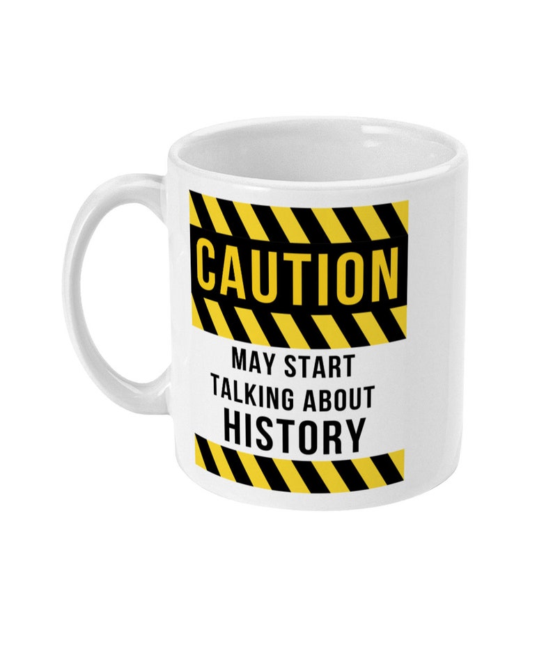 K&ouml;nnte beinhalten: Wei&szlig;e Keramiktasse mit einem schwarzen und gelben Warnschild mit der Aufschrift "ACHTUNG KANN ANFANGEN &Uuml;BER GESCHICHTE ZU REDEN".