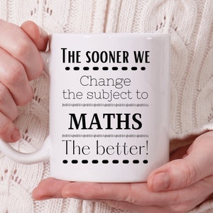 May include: White ceramic mug with black text that reads "THE SOONER WE Change the subject to MATHS The better!" The mug is held by a person wearing a cream-colored sweater.