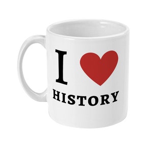 K&ouml;nnte beinhalten: Wei&szlig;e Keramiktasse mit einem schwarzen "Ich liebe Geschichte"-Design. Das Wort "liebe" wird durch ein rotes Herz ersetzt.