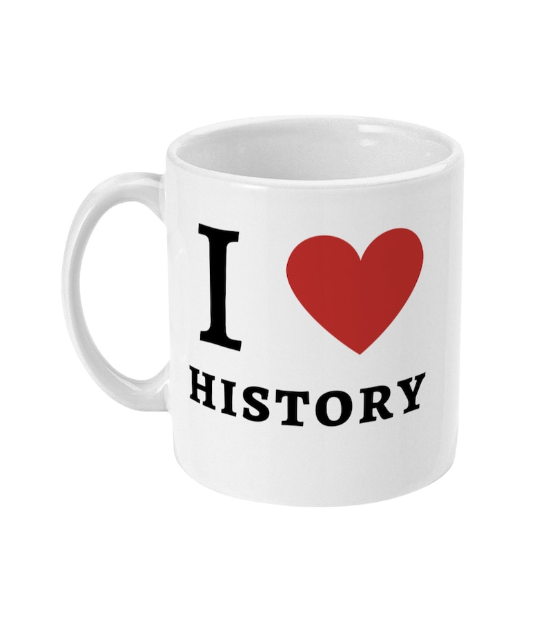 K&ouml;nnte beinhalten: Wei&szlig;e Keramiktasse mit einem schwarzen "Ich liebe Geschichte"-Design. Das Wort "liebe" wird durch ein rotes Herz ersetzt.