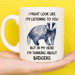 May include: White ceramic mug with a black and white illustration of a badger. The mug has the text "I might look like I'm listening to you, but in my head I'm thinking about badgers."
