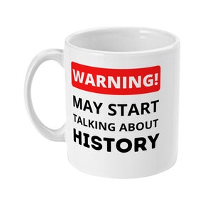 K&ouml;nnte beinhalten: Wei&szlig;e Keramiktasse mit einem roten und schwarzen Warnschild mit der Aufschrift "ACHTUNG! K&Ouml;NNTE ANFANGEN, &Uuml;BER GESCHICHTE ZU REDEN".