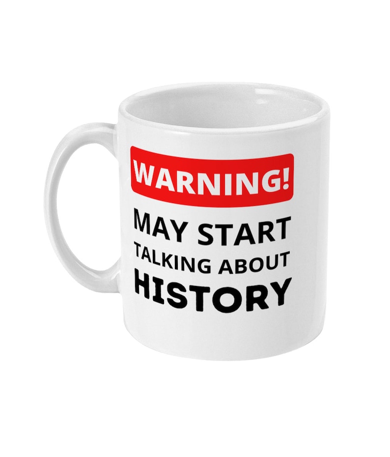 K&ouml;nnte beinhalten: Wei&szlig;e Keramiktasse mit einem roten und schwarzen Warnschild mit der Aufschrift "ACHTUNG! K&Ouml;NNTE ANFANGEN, &Uuml;BER GESCHICHTE ZU REDEN".