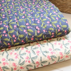 Pu&ograve; includere: Due pezzi di tessuto trapuntato piegati con un motivo floreale. Lo strato superiore &egrave; blu scuro con fiori rosa simili a tulipani e foglie verdi. Lo strato inferiore &egrave; color crema con lo stesso motivo floreale stampato in rosa e verde.