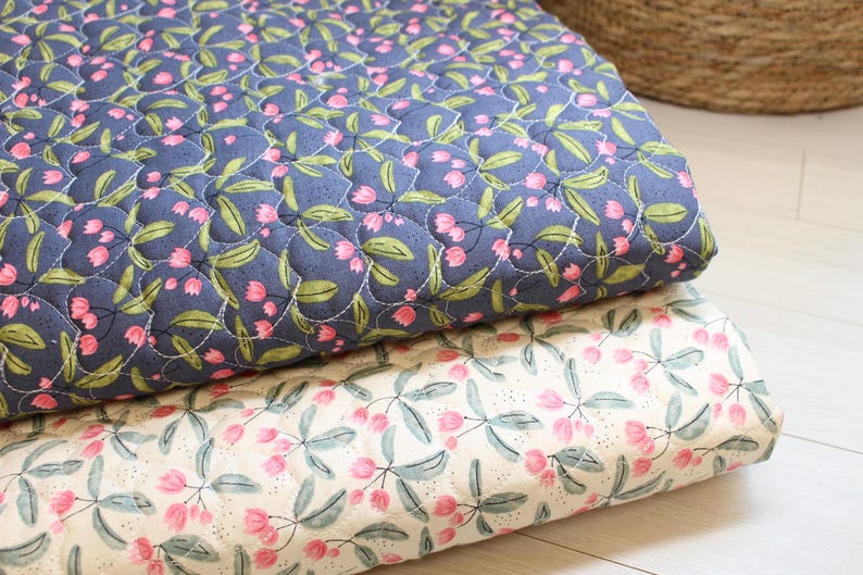 Pu&ograve; includere: Due pezzi di tessuto trapuntato piegati con un motivo floreale. Lo strato superiore &egrave; blu scuro con fiori rosa simili a tulipani e foglie verdi. Lo strato inferiore &egrave; color crema con lo stesso motivo floreale stampato in rosa e verde.