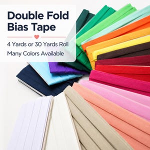 May include: Double Fold Bias Tape in a variety of colors. The image shows stacks of folded bias tape in shades of white, beige, pink, red, purple, blue, green, yellow, and brown. The text on the image says "Double Fold Bias Tape" and "Many Colors Available."