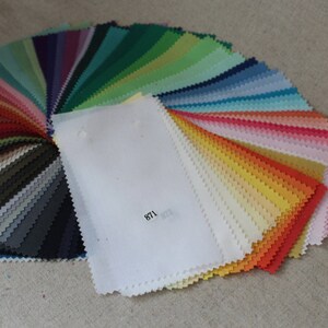 Puede incluir: Una carta de colores en forma de abanico de muestras de tela en varios tonos de verde, azul, rosa, naranja, amarillo y gris. Las muestras est&aacute;n dispuestas en un patr&oacute;n de arco&iacute;ris. Una muestra de tela blanca con el n&uacute;mero "871" impreso en ella est&aacute; en el centro del abanico.