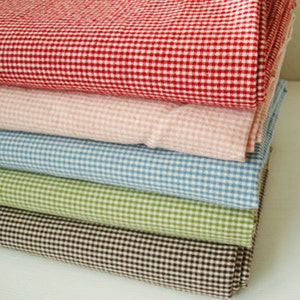 May include: A stack of five gingham fabrics in different colours: red, pink, blue, green, and brown. The fabric has a small checkered pattern.
