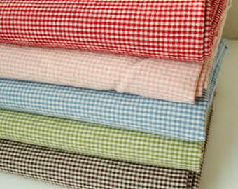 May include: A stack of five gingham fabrics in different colors: red, pink, blue, green, and brown. The fabric has a small checkered pattern.